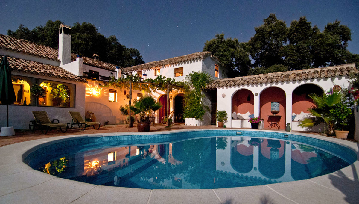 A large house with a round swimming pool at night