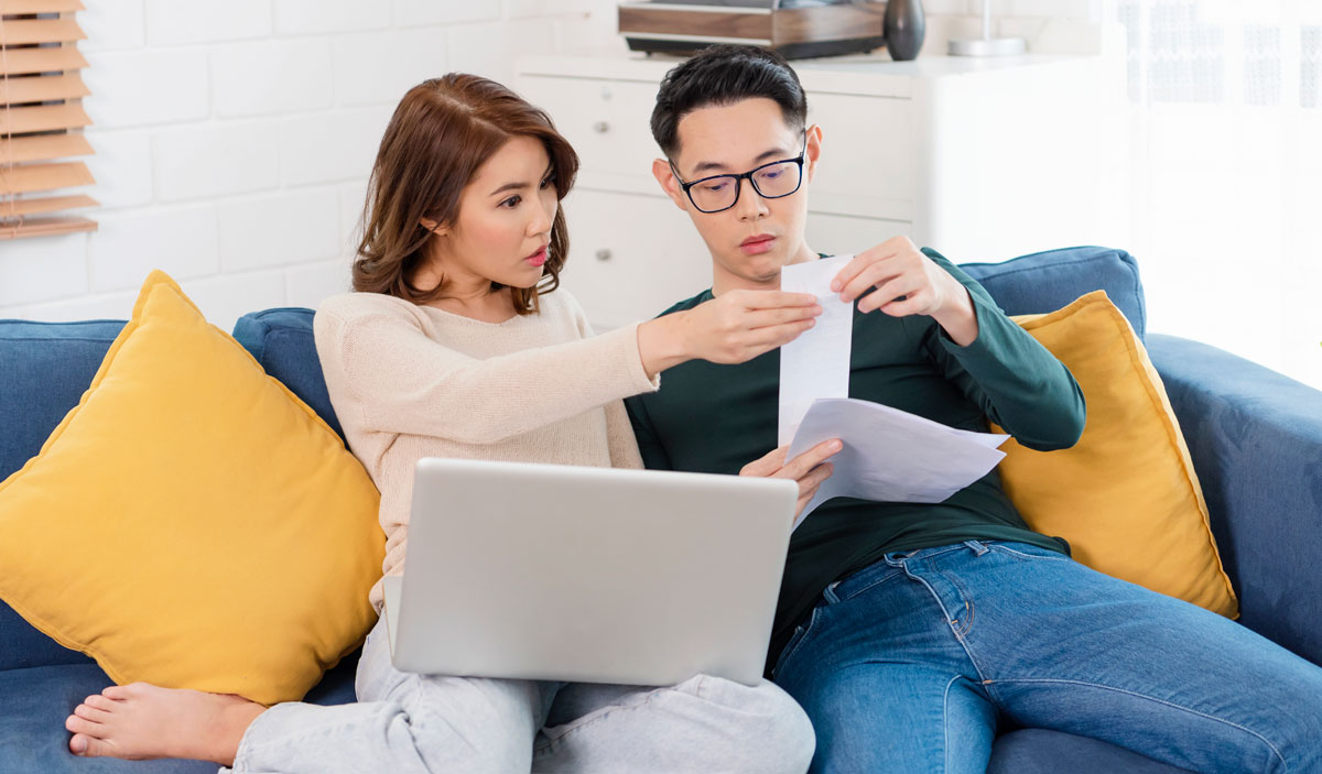 A man and woman checking analyzing statement utilities bills sitting together at home