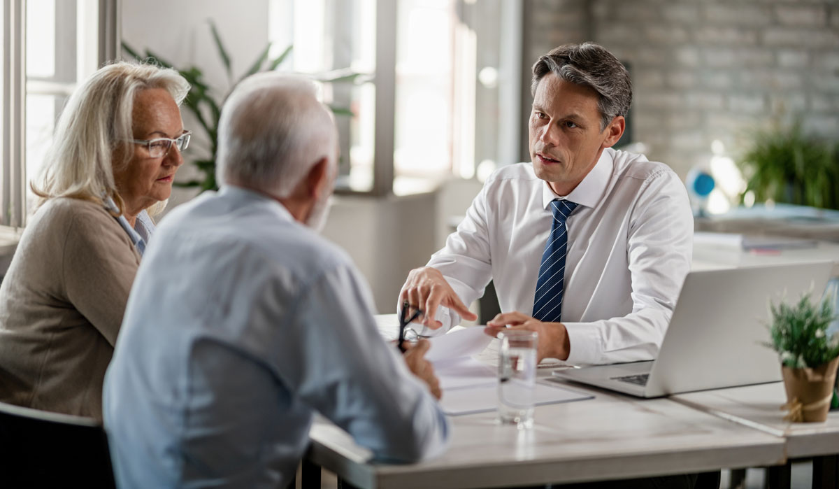 agent with mature couple analyzing financial reports and communicating during the meeting in the office 