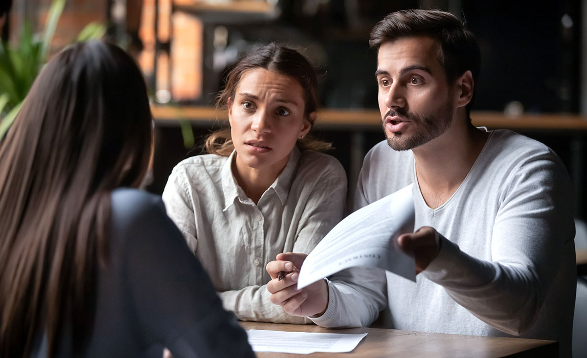 Annoyed angry disappointed tenant couple holding paper arguing with landlord