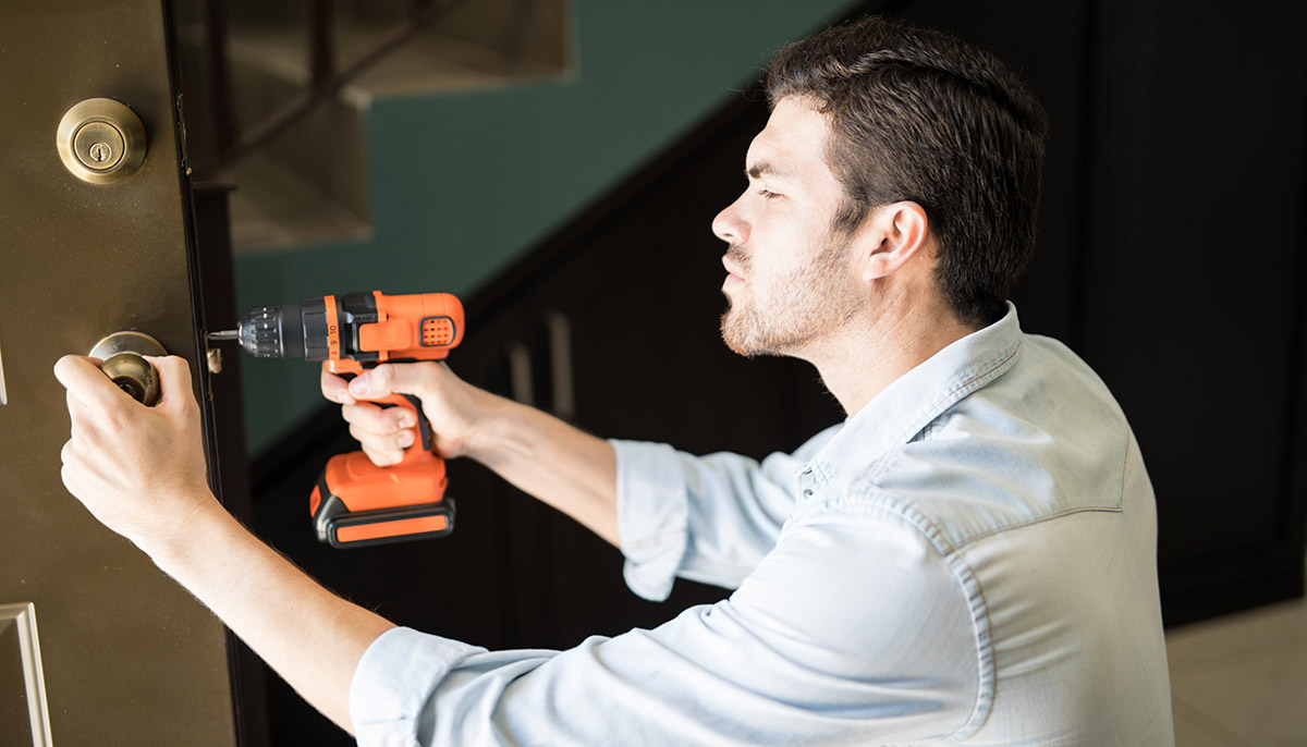 an handyman using a power drill to chnage the door lock