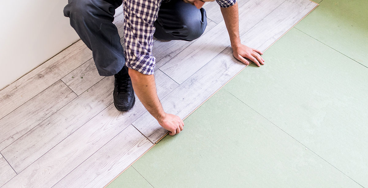 Worker processing a floor with bright laminated flooring boards