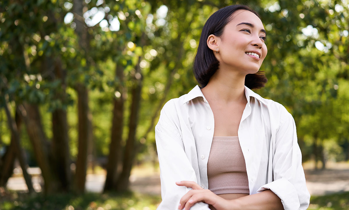 girl walking in park smiling while having a mindful walk in woods