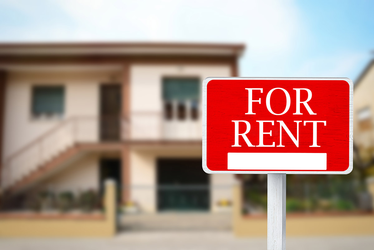 Sign with phrase for rent and blurred view of beautiful house