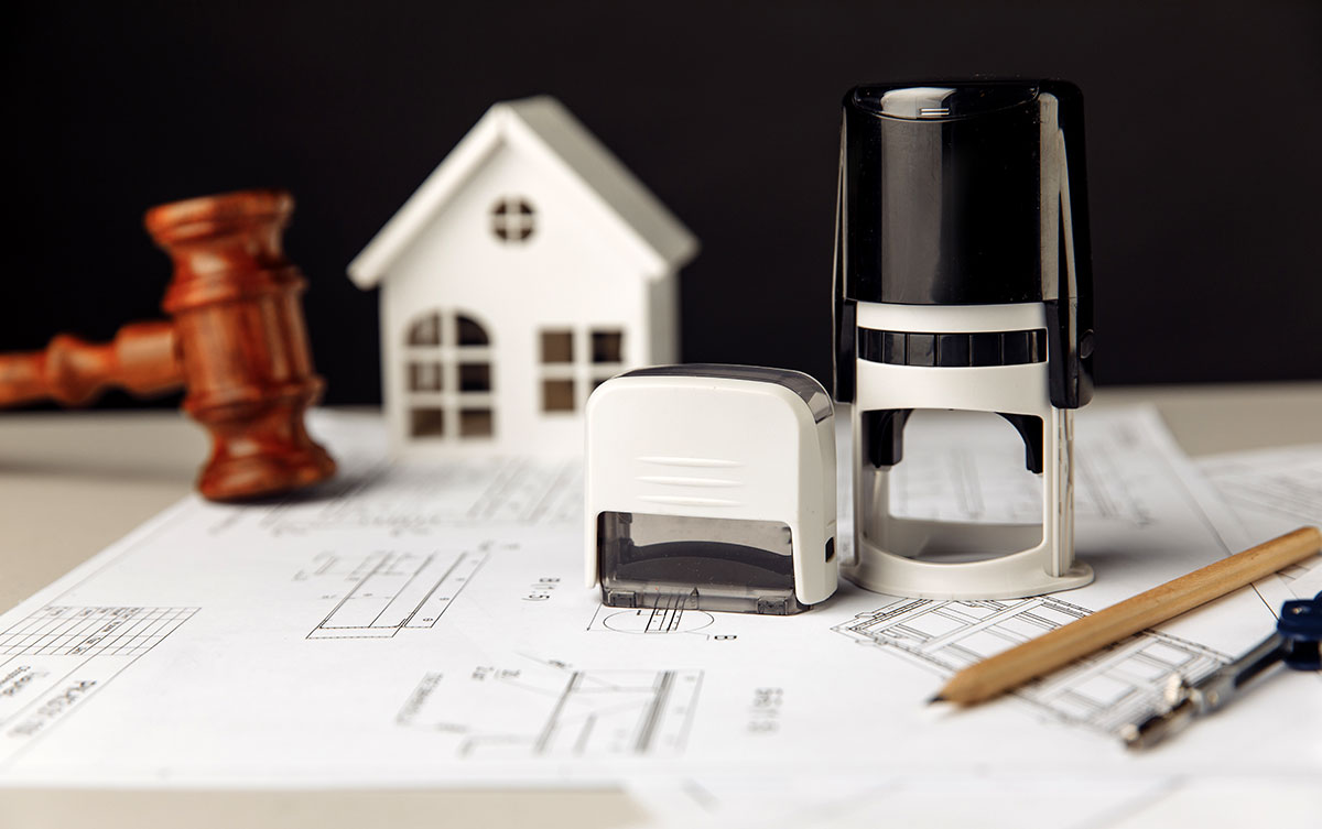Judge wooden gavel stamp and model of house with blueprint