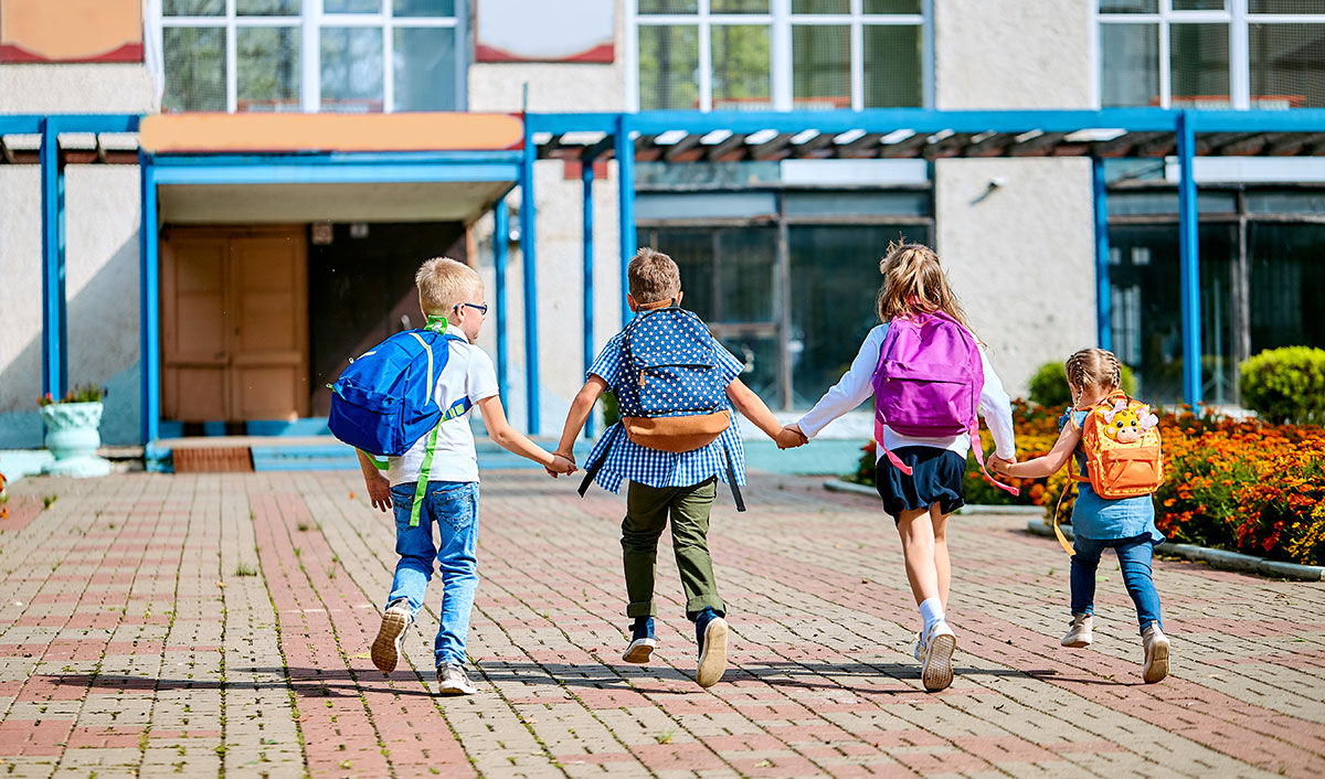 School children with backpacks running out of school