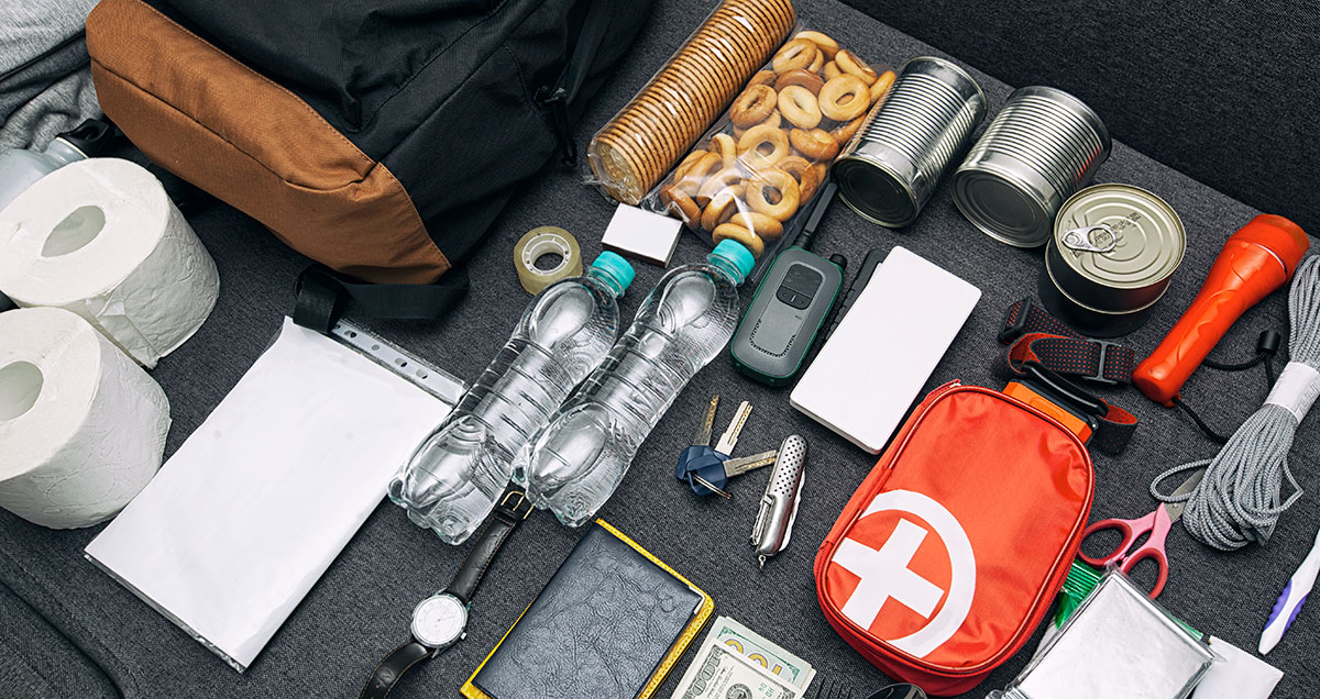 Emergency backpack equipment organized on the table documents waterfood first aid kit and another items needed to
