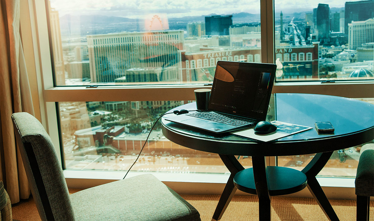 Macbook pro on the table with a view of the city in the background.