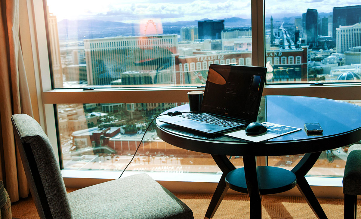 Home office setup with a laptop on a glass table overlooking panoramic views