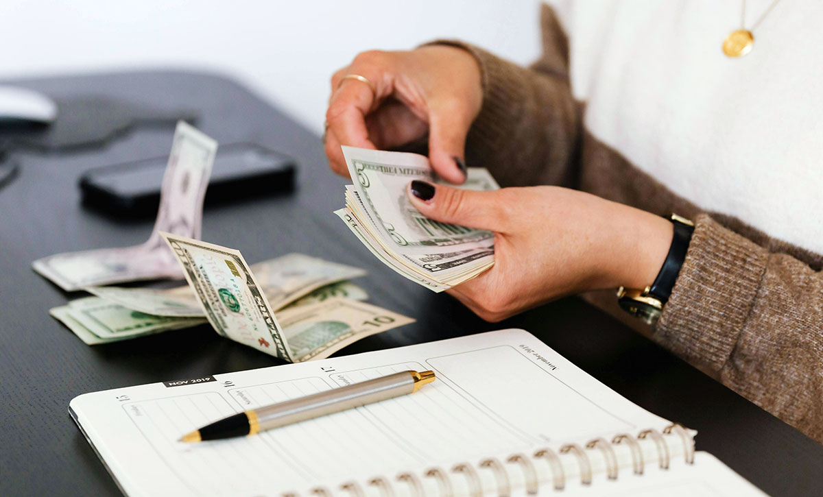A person counting money in front of a desk