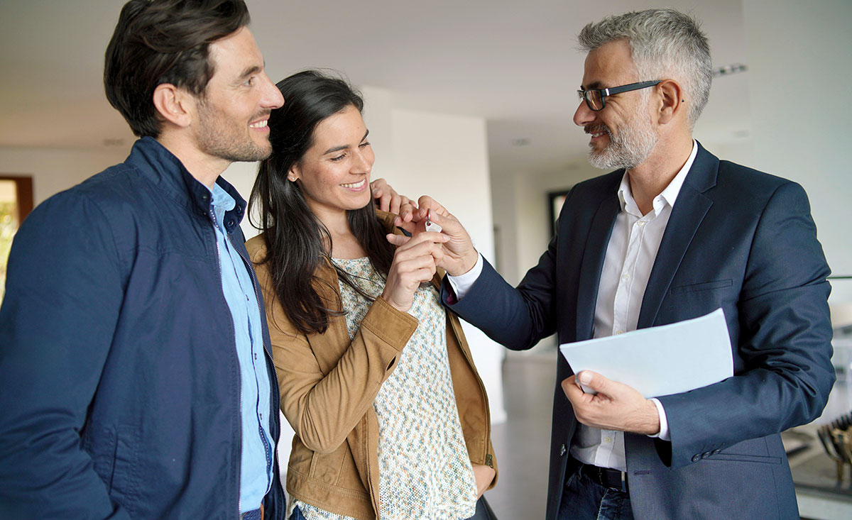 Couple with real-estate agent looking at contract in modern house
