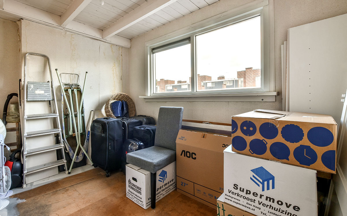 A room with boxes and a window and a ladder